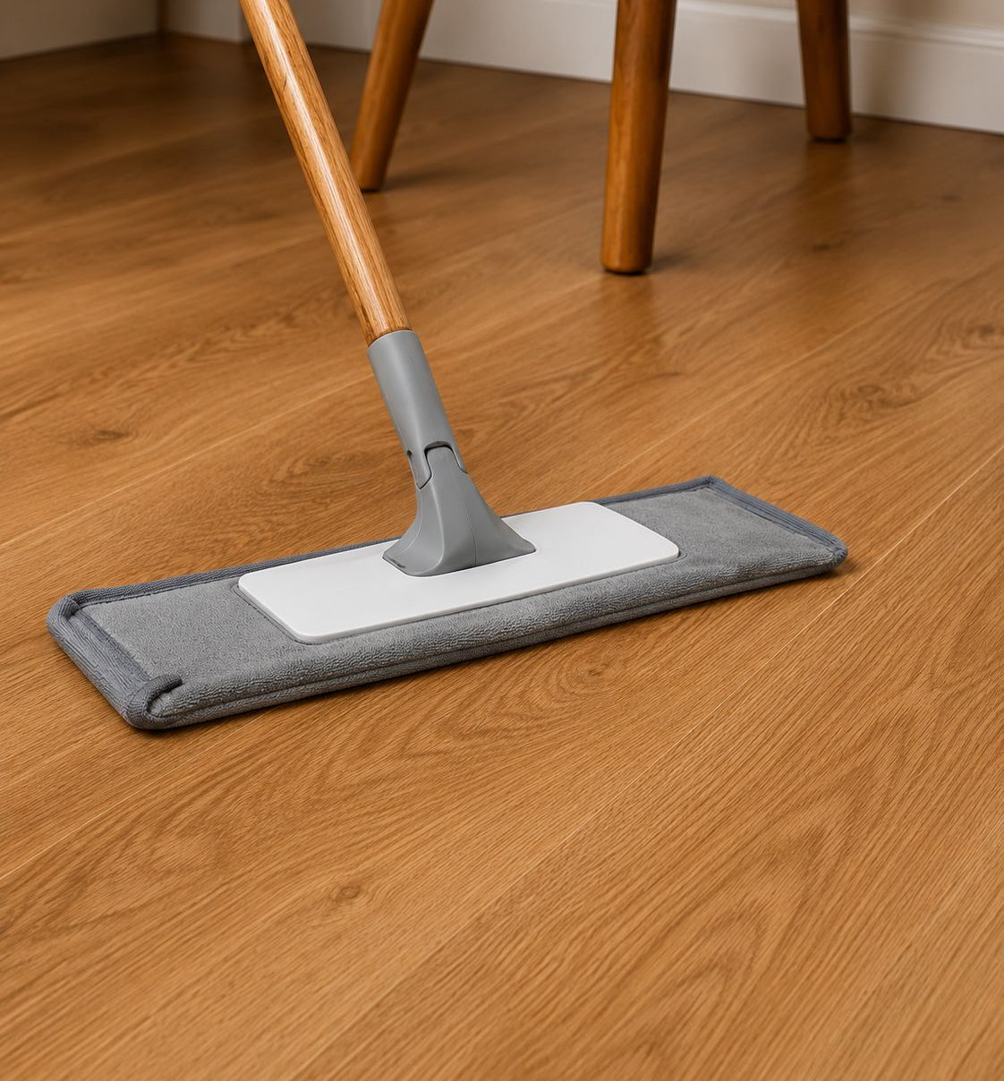 Mop with a gray head and white handle on a wooden floor