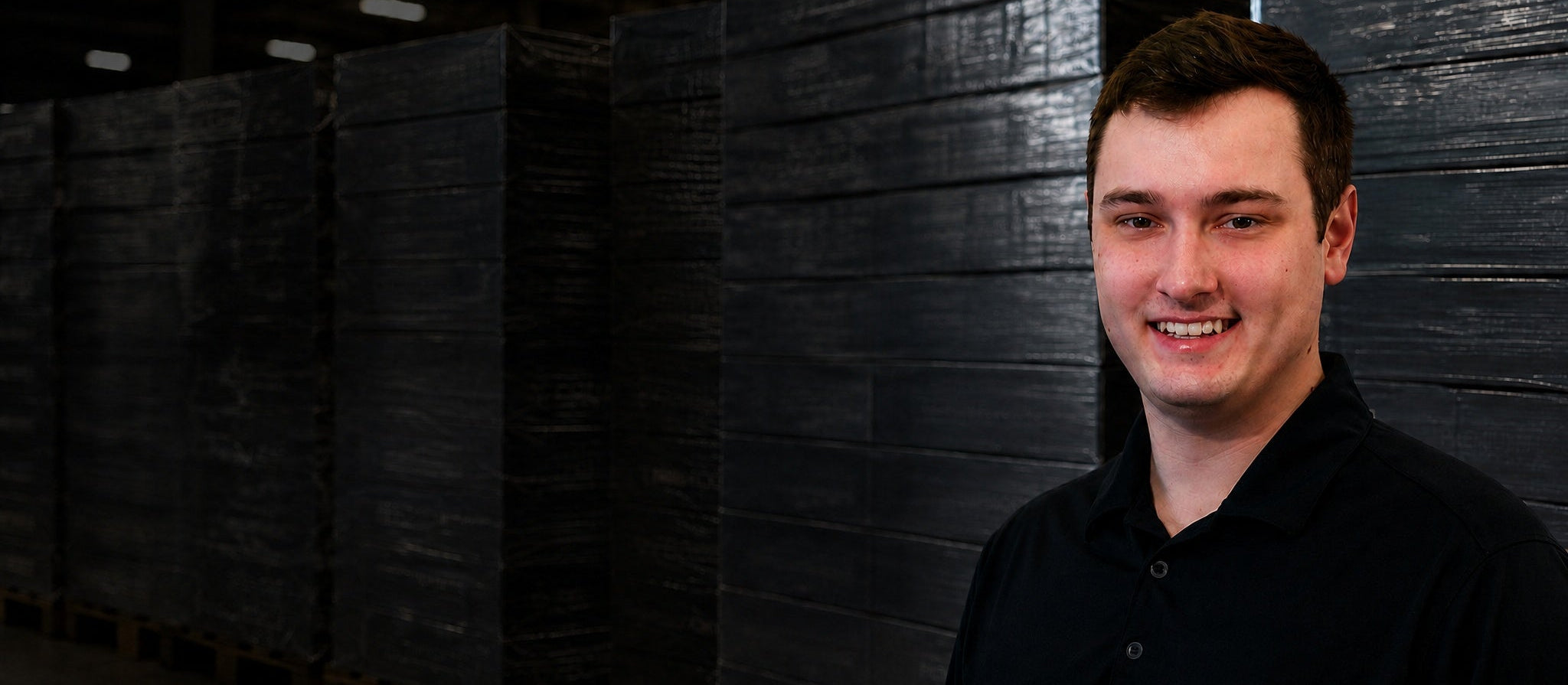 Man standing in a warehouse with stacked pallets in the background